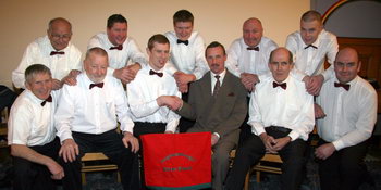 David Corbett, secretary of Aughnaskeagh Silver Band congratulates conductor Gary Shields, whose top class results in the Open University MA in Music exam last October, placed him in the top 12% in the UK. The band members are pictured at the Carol Service in Dromore Orange Hall last Thursday evening (11th December). L to R: (front) Mervyn Rolston, Sammy Skelly (Chairman), David Corbett (Secretary), Gary Shields (Conductor), Harold Graham and Alan Graham. (back row) Verdin Graham, Colin Hamilton, Aaron Hamilton, Mark Hamilton and Christopher McCandless.