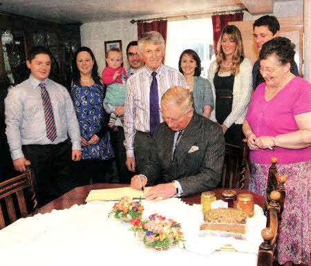 Prince Charles sign's the visitor's book at the Tuft family home, with John and Heather Tuft and their family circle.