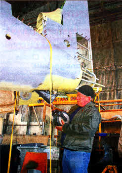 UAS member Mal Deeley checks the fit of the Wildcat's tailwheel to the fuselage. The missing tailhook retracts into the extreme end of the aircraft's tail. The pilot would operate a control to drop the device into position for landing aboard an aircraft carrier. (Picture by Stephen Riley)