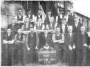 Netting set is Complete,Last week's old picture of the women who worked in the netting department of William Barbour and Sons, Hilden prompted Mr. Derick Coburn of 23, Lawnbrook Drive, Hilden, to complete the picture by submitting this phptograph  of the men who worked in the department at the same time. March 3, 1938. Mr. Coburn, whose father, Mr. Fred Coburn, time and cost clerk and Later, overlooker, Is on the extreme right front row, says many workers are missing from the photographs including night shift. workers. Back row (left to right) are Dan Marmian, Billy Bleakes, Tommy Topping, Bobby McMaster, Davy Bell, Billy Carnahan, clerk and later overlooker. Middle row, Stanley McCurley, Jim Hayden, Billy Gibson, Richard Hayden, Tommy Ringland, John Williamson overlooker. Front row, Eddie Jefferson, Tommy Watters, Frank Kennedy, Bertie Hanna, manager: Billy Bell, Billy McCurley and Mr. Coburn. E1852.	.